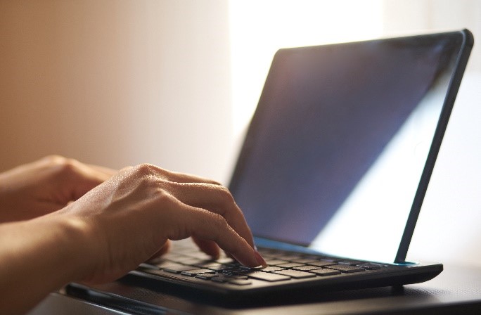 Zwei Hände tippen auf einer Tastatur an einem Tablet