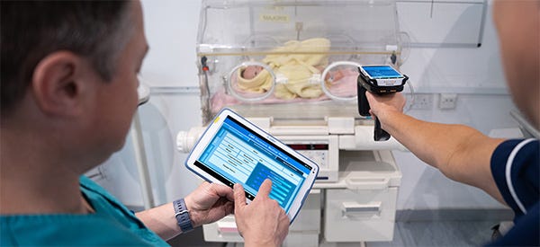 Ärztliches Pflegepersonal, das mithilfe von RFID-Handheld und RFID-Tablet Daten eines Babyinkubators aufnimmt