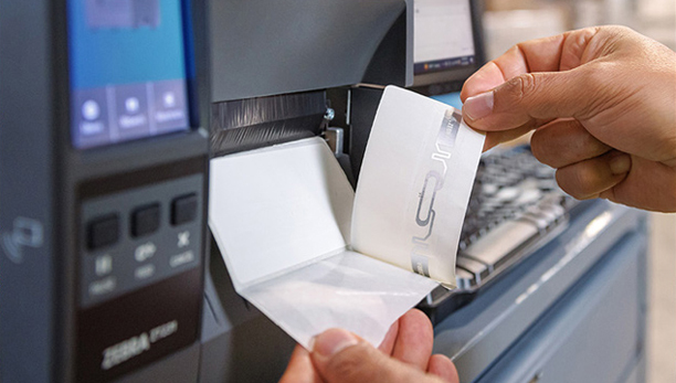 Anwendungsbild mit einem RFID-Etikettendrucker und eine Hand, die gedruckte Etiketten entnimmt
