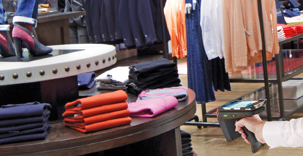 Anwendungsbild zum Thema RFID im Handel auf dem ein Kleidungsgeschäft zu sehen ist, indem per RFID-Handheld Kleidungsstücke gescannt werden