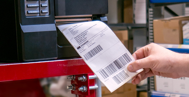 Versandetikett, das gerade gedruckt wird und von einem Mitarbeiter aus dem Etikettendrucker entnommen wird